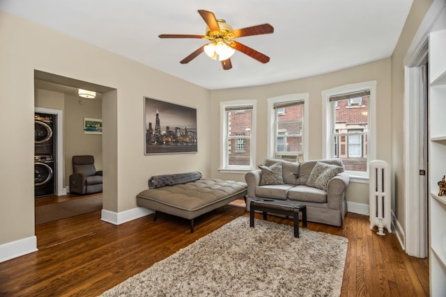 132 Clyde Ave Unit 1, Evanston, IL 60202 - living area featuring stacked washing machine and dryer, radiator heating unit, ceiling fan, and dark wood-type flooring
