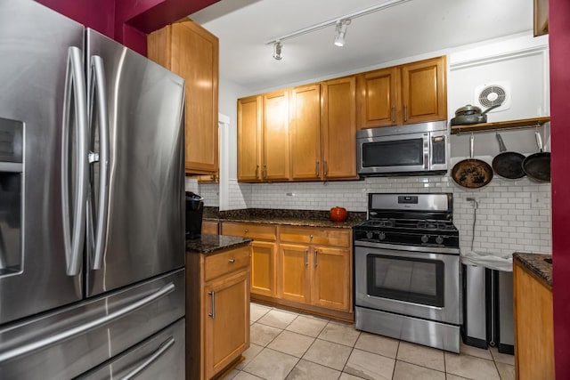 132 Clyde Ave Unit 1, Evanston, IL 60202 - kitchen featuring stainless steel appliances, light tile patterned floors, decorative backsplash, and dark stone countertops