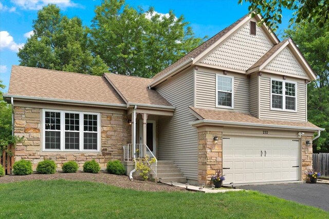 232 Lexington Ct, Grayslake, IL 60030 - view of front facade with stone siding, a garage, asphalt driveway, a shingled roof, and a front lawn