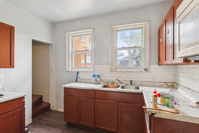 8136 S Manistee Ave, Chicago, IL 60617 - kitchen featuring white microwave, dark wood-style floors, light countertops, tasteful backsplash, and brown cabinets