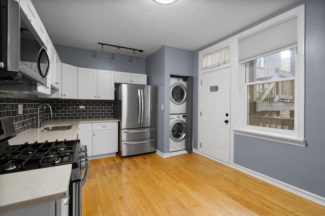 5000 N Glenwood Ave Unit 2, Chicago, IL 60640 - kitchen with stainless steel appliances, stacked washer / drying machine, light countertops, white cabinetry, and decorative backsplash