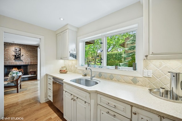1728 Wildberry Dr Unit B, Glenview, IL 60025 - kitchen with stainless steel dishwasher, light countertops, white cabinetry, a brick fireplace, and light wood-type flooring