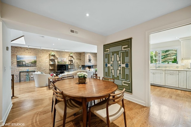 1728 Wildberry Dr Unit B, Glenview, IL 60025 - dining area featuring a brick fireplace, light wood-style flooring, brick wall, and recessed lighting