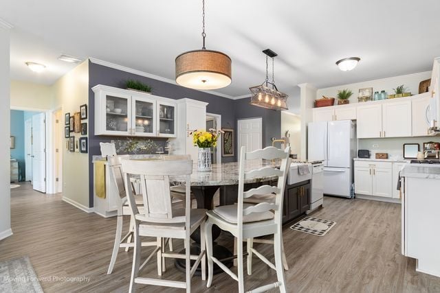 17228 Fontana Ln, Lockport, IL 60441 - kitchen with white appliances, white cabinetry, light wood-style floors, a kitchen breakfast bar, and ornamental molding
