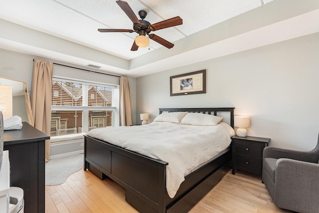 390 W Mahogany Ct Unit 301, Palatine, IL 60067 - bedroom with light wood-style flooring, a tray ceiling, and a ceiling fan