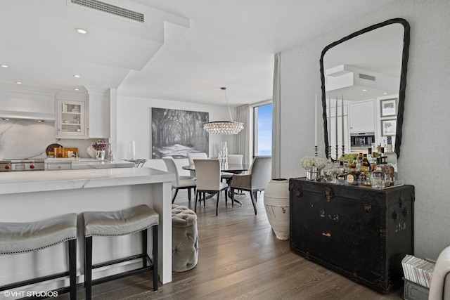 990 N Lake Shore Dr Unit 10A, Chicago, IL 60611 - kitchen with white cabinets, dark wood-style flooring, a kitchen breakfast bar, glass insert cabinets, and pendant lighting