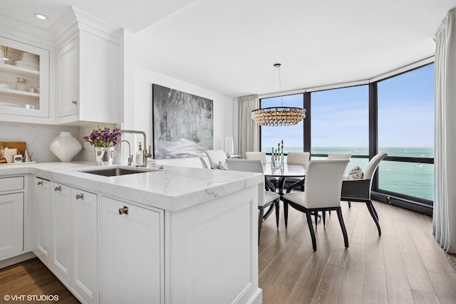 990 N Lake Shore Dr Unit 10A, Chicago, IL 60611 - kitchen featuring light wood-style floors, floor to ceiling windows, white cabinets, a chandelier, and light stone counters