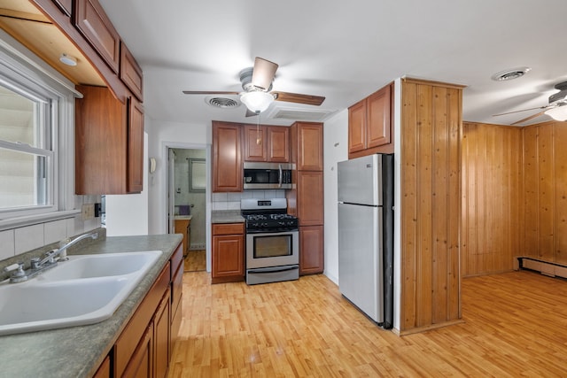 1811 Dearborn St, Crest Hill, IL 60403 - kitchen with stainless steel appliances, a ceiling fan, light wood finished floors, brown cabinets, and wood walls