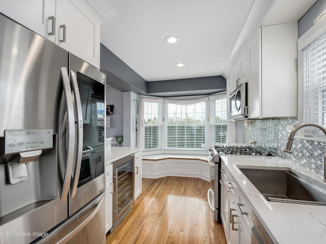 7215 W Foster Ave, Harwood Heights, IL 60706 - kitchen with appliances with stainless steel finishes, wine cooler, light wood-style flooring, white cabinetry, and recessed lighting
