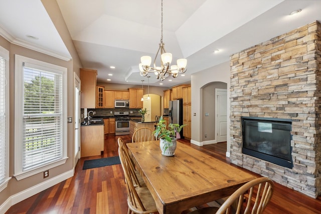 207 Quinlan Ave, Dekalb, IL 60115 - dining area with arched walkways, a chandelier, dark wood-type flooring, a stone fireplace, and ornamental molding
