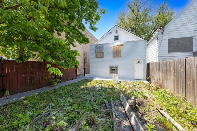 rear view of property with a vegetable garden and a fenced backyard