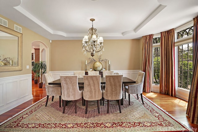 1400 Banbury Rd, Inverness, IL 60067 - dining room with a tray ceiling, a chandelier, arched walkways, wood finished floors, and a wainscoted wall
