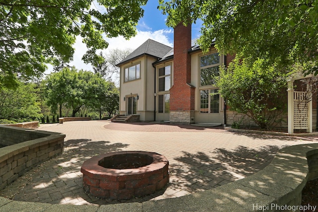 1400 Banbury Rd, Inverness, IL 60067 - rear view of house featuring a fire pit, a patio, stone siding, and stucco siding