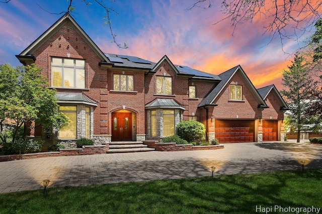 1400 Banbury Rd, Inverness, IL 60067 - view of front of home featuring driveway, brick siding, roof mounted solar panels, an attached garage, and stone siding