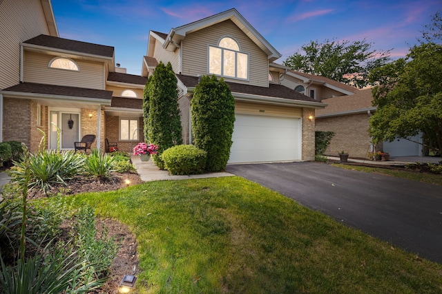 view of front facade with asphalt driveway, brick siding, a garage, and a lawn