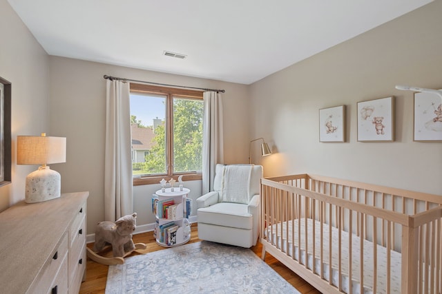 bedroom featuring wood finished floors and a nursery area