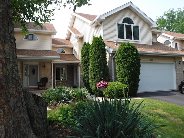 view of front facade featuring asphalt driveway, roof with shingles, and brick siding