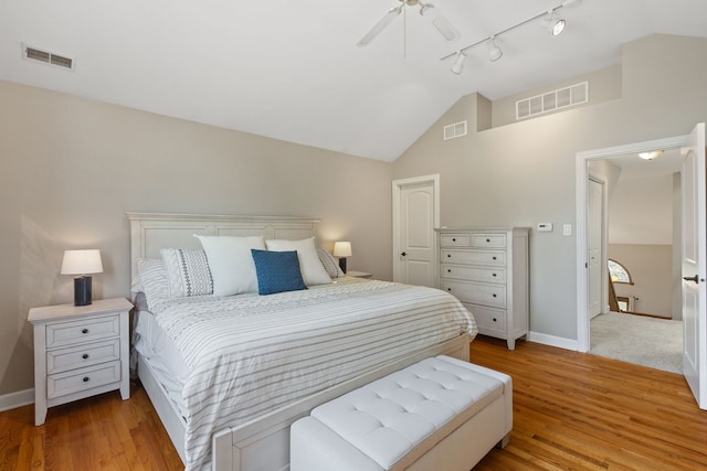 bedroom featuring lofted ceiling, rail lighting, light wood-type flooring, and ceiling fan