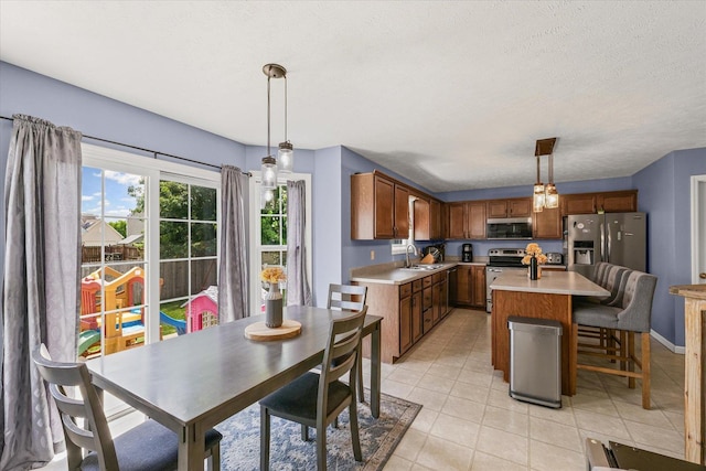 3905 Boulder Ridge Dr, Champaign, IL 61822 - kitchen featuring stainless steel appliances, light countertops, light tile patterned floors, decorative light fixtures, and a kitchen island