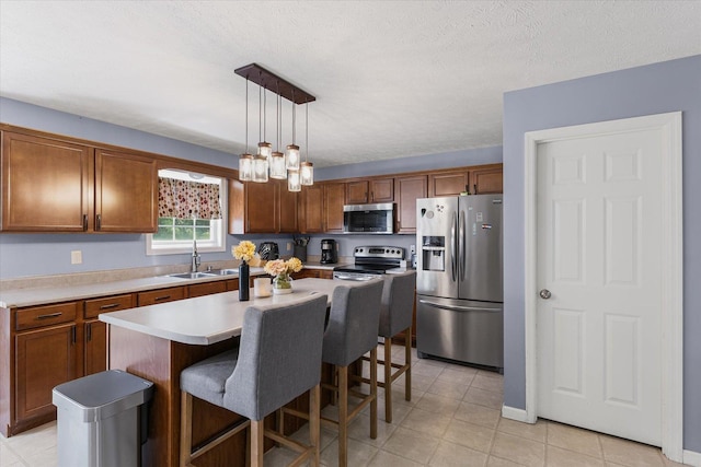 3905 Boulder Ridge Dr, Champaign, IL 61822 - kitchen with stainless steel appliances, brown cabinetry, light countertops, a kitchen bar, and a textured ceiling