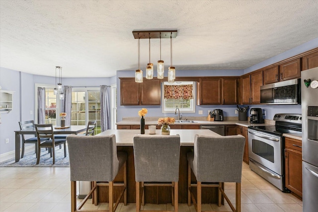 3905 Boulder Ridge Dr, Champaign, IL 61822 - kitchen featuring appliances with stainless steel finishes, light countertops, a kitchen breakfast bar, a kitchen island, and a textured ceiling