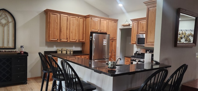 6638 Key Largo Dr, Machesney Park, IL 61103 - kitchen with appliances with stainless steel finishes, vaulted ceiling, a peninsula, light wood-style floors, and a breakfast bar area