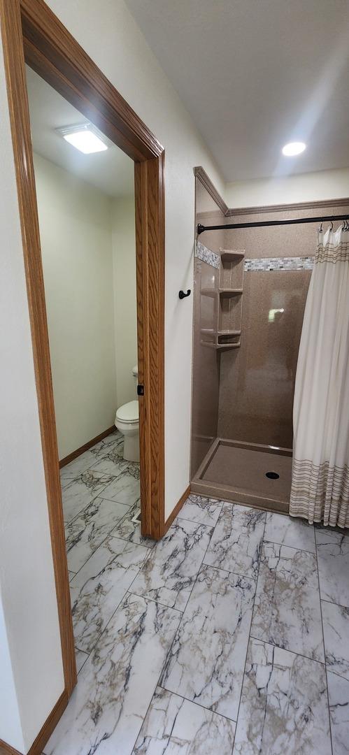 6638 Key Largo Dr, Machesney Park, IL 61103 - bathroom featuring marble finish floors, baseboards, a stall shower, and toilet
