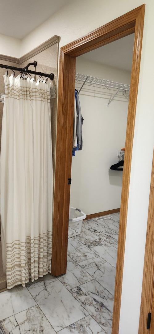 6638 Key Largo Dr, Machesney Park, IL 61103 - bathroom featuring marble look tile flooring, a shower with curtain, and baseboards