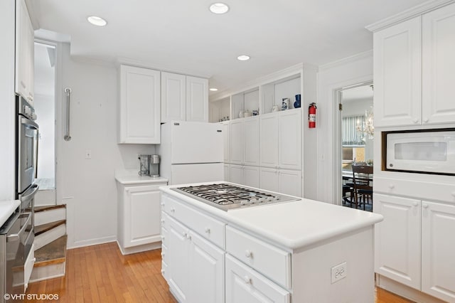 1241 Forest Ave, Wilmette, IL 60091 - kitchen with stainless steel appliances, recessed lighting, light wood-style flooring, white cabinets, and ornamental molding