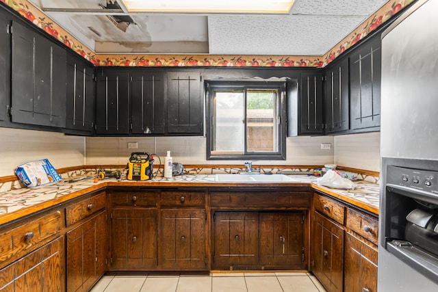 14217 Turner Ave, Robbins, IL 60472 - kitchen with stainless steel fridge, a sink, light tile patterned floors, and dark cabinets