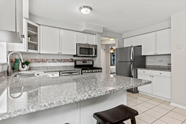 4730 N Hermitage Ave Unit 3C, Chicago, IL 60640 - kitchen with appliances with stainless steel finishes, white cabinets, a breakfast bar, glass insert cabinets, and light stone counters