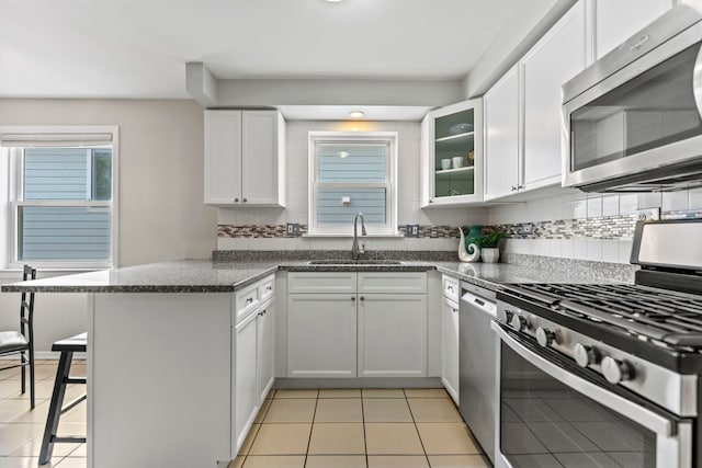4730 N Hermitage Ave Unit 3C, Chicago, IL 60640 - kitchen with stainless steel appliances, a peninsula, light tile patterned flooring, a kitchen bar, and decorative backsplash
