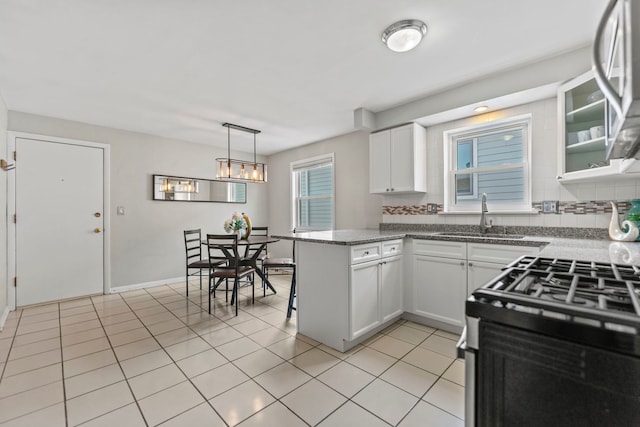 4730 N Hermitage Ave Unit 3C, Chicago, IL 60640 - kitchen with a peninsula, white cabinetry, range with gas cooktop, light tile patterned floors, and glass insert cabinets