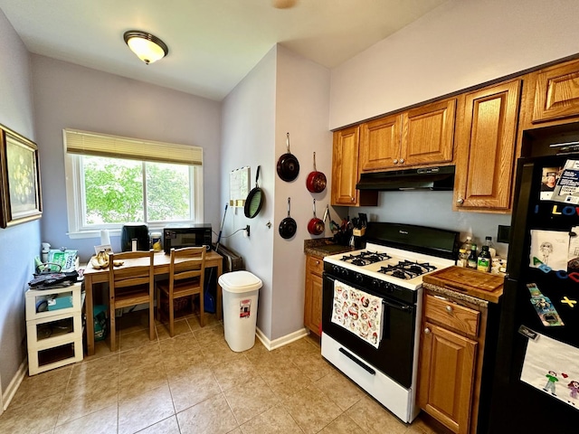 478 Barrett St, Elgin, IL 60120 - kitchen with under cabinet range hood, range with gas cooktop, freestanding refrigerator, and brown cabinetry