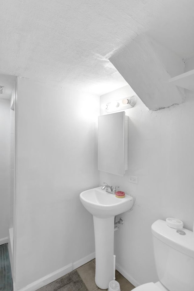 1205 N Irving Ave, Berkeley, IL 60163 - bathroom with toilet, baseboards, a textured ceiling, and a bath
