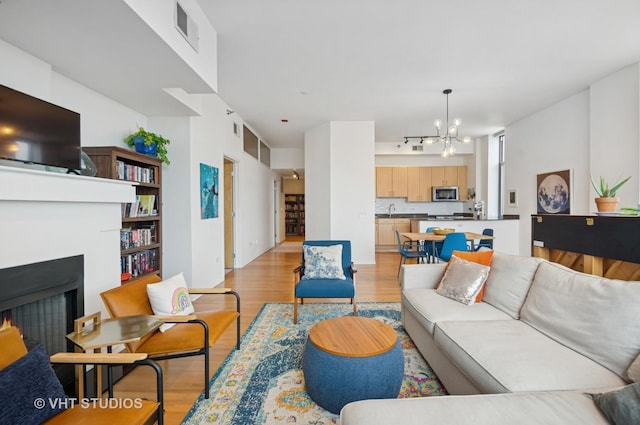 1201 W Adams St Unit 1001, Chicago, IL 60607 - living room featuring a chandelier, light wood finished floors, and a lit fireplace