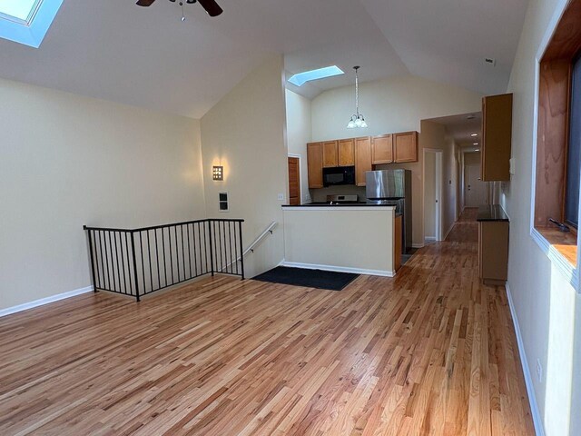 3037 W Polk Ave Unit 3, Chicago, IL 60612 - kitchen with a skylight, black microwave, dark countertops, light wood finished floors, and high vaulted ceiling