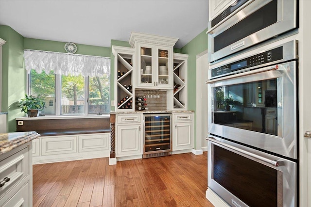 1810 Cardinal Ct, Pontiac, IL 61764 - kitchen featuring beverage cooler, appliances with stainless steel finishes, light wood finished floors, glass insert cabinets, and light stone counters
