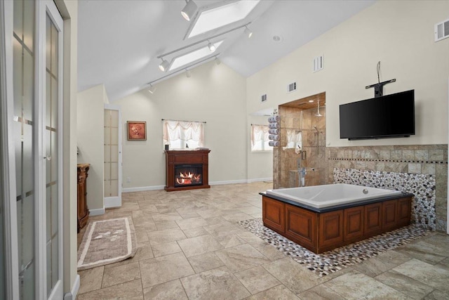 1810 Cardinal Ct, Pontiac, IL 61764 - bathroom with a bath, a stall shower, a glass covered fireplace, stone finish flooring, and rail lighting