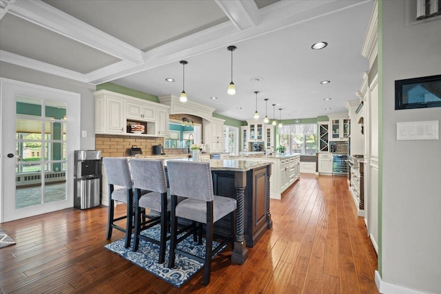 1810 Cardinal Ct, Pontiac, IL 61764 - kitchen featuring a center island with sink, a breakfast bar area, beam ceiling, glass insert cabinets, and dark wood-style floors