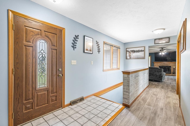 9650 Edgefield Rd, Roscoe, IL 61073 - foyer entrance featuring a textured ceiling, baseboards, a fireplace, light wood-type flooring, and a ceiling fan