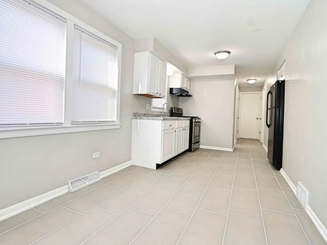 7056 S Honore St, Chicago, IL 60636 - kitchen with freestanding refrigerator, gas stove, white cabinetry, light countertops, and light tile patterned floors