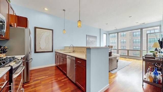 3920 N Sheridan Rd Unit 411, Chicago, IL 60613 - kitchen featuring stainless steel appliances, a peninsula, wood finished floors, hanging light fixtures, and light countertops
