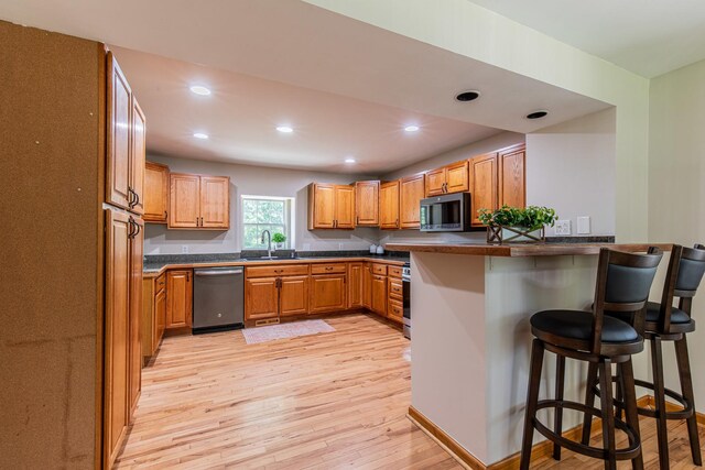 402 Lincoln St, Seatonville, IL 61359 - kitchen with stainless steel appliances, a breakfast bar area, light wood-style flooring, dark countertops, and recessed lighting