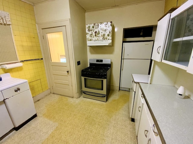 157 Prairie St, Ottawa, IL 61350 - kitchen with gas stove, under cabinet range hood, freestanding refrigerator, white cabinets, and light countertops