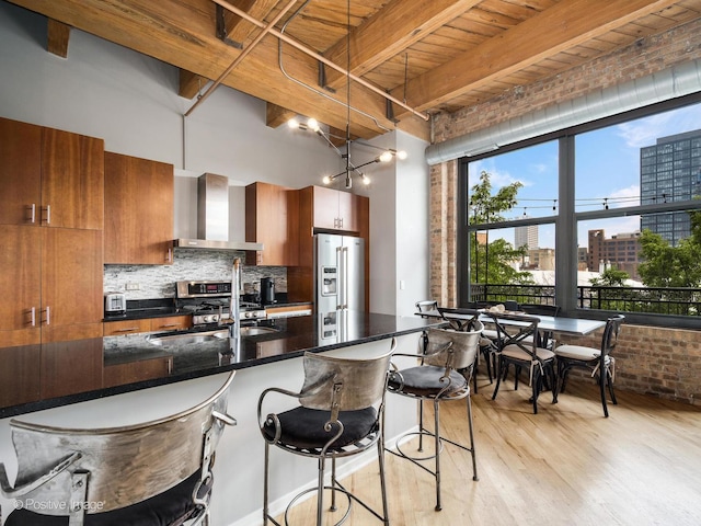 1040 W Adams St Unit 238, Chicago, IL 60607 - kitchen featuring wall chimney exhaust hood, brown cabinetry, stainless steel appliances, light wood finished floors, and decorative backsplash