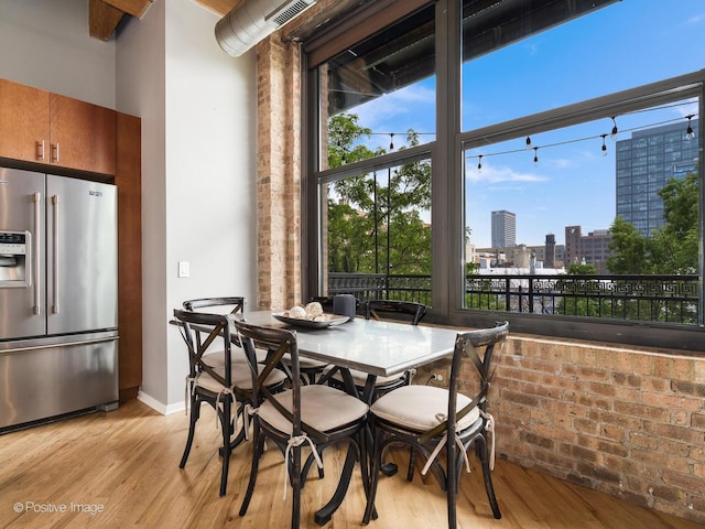 1040 W Adams St Unit 238, Chicago, IL 60607 - dining space featuring a view of city, brick wall, light wood-type flooring, and baseboards
