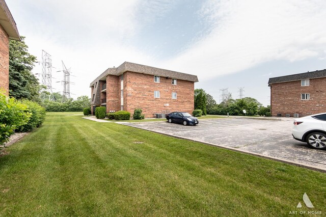 9146 W 140th St Unit 2Sw, Orland Park, IL 60462 - view of side of home featuring uncovered parking, a lawn, and brick siding