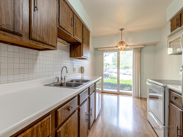 500 W Huntington Commons Rd Unit 150, Mount Prospect, IL 60056 - kitchen featuring white appliances, light wood-type flooring, decorative backsplash, light countertops, and hanging light fixtures
