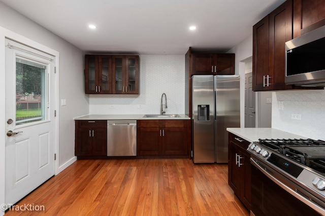 6943 Parkview Dr, Downers Grove, IL 60516 - kitchen featuring stainless steel appliances, light countertops, light wood-style floors, backsplash, and glass insert cabinets